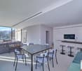modern open plan living room with dining area, large windows, glass table, modern chairs, gray sofa, kitchen island, modern kitchen