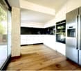 modern kitchen with wooden floor, white cabinets, black marble countertop, stainless steel appliances, glass door