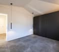 Large room with white walls, tiled floor, large black sliding closets, entrance door, wall switches, pendant lighting.