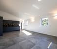 Empty room, large windows, grey tiles, black kitchen, built-in light