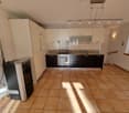 Modern kitchen with white and black cabinets, tiled floor, gas stove, oven, and a fireplace