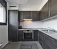 Modern kitchen with dark gray cabinets, granite countertops, built-in oven and stove, and a dishwasher