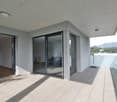 Spacious apartment with large windows, sliding glass doors leading to a balcony or terrace, hardwood floors, and a view of the surrounding mountains.