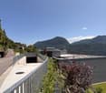 modern house, raised ground floor, concrete driveway, metal railing, green lawn, mountain view