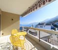 Balcony with yellow patio furniture, overlooking a scenic view of mountains and buildings