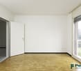 Empty room with white walls, hardwood flooring, and a sliding glass door leading to a balcony or terrace.