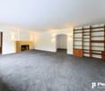 large room, carpet, white walls, fireplace, two doors, shelf