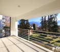 Modern balcony with tiled floor, stainless steel railings, and panoramic views of the surroundings.