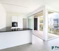 modern kitchen with island, black countertops, white cabinets, large windows, balcony