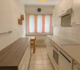 wood cabinets, white walls, tiled floor, radiator, large window, kitchen table, kitchen stove, dishwasher, washing machine