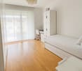 single bed, white cabinet, desk, white chair, sliding windows, ceiling lamp, wooden floor