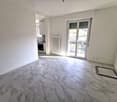 empty room, white walls, marble flooring, sliding glass doors to balcony, heater, kitchen area with oven