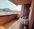 Balcony with wooden floor, table with flowers, vase, mountains view