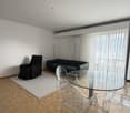modern living room with a couch, a recliner, a glass table, and a white rug