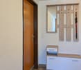 Entryway with wooden door, wooden cabinet with drawers, coat rack with ski poles, mirror