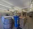 spacious store, shelves, counter, blue recycle bin, wooden barrel, tiled floor, ceiling lights