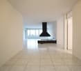 white tiled floor, white walls, large windows, black modern chimney, wooden bench