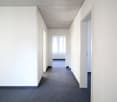Empty corridor with carpet flooring and white walls