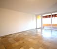 Empty room with tiled floor, white walls, sliding glass doors leading to balcony, and ceiling light