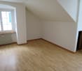 empty room, wooden floor, white walls, radiator, window, slanted ceiling