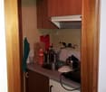 a small kitchen with a sink, stove, cabinets, countertop, dishwasher, cabinet, faucet, and other kitchen appliances.