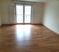 Empty room with hardwood floors, sliding glass door to balcony, white walls, radiator on the wall.