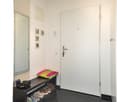black speckled floor, white walls, shoes in shoe rack, large mirror, two wall picture frames, light fixtures