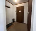Empty room with carpeted floor, door, hallway, and wall hook