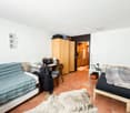 spacious room with two beds, wooden cabinets, desk, office chair, animal skin rug, white walls, and tiled floor