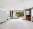 Empty room with white walls, white tile, large window with view, wooden shelves