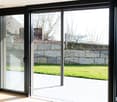 Sliding doors, glass wall, outdoor deck, grassy lawn, stone wall