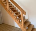 Wooden stairs with a simple, open design. The stairs have a natural wood finish and a clean, minimalist aesthetic.