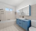 white and blue bathroom with bathtub, shower, sink, and toilet