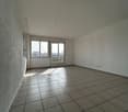 Large room with windows and balcony overlooking the city. Light tiles on the floor. Tiled walls.