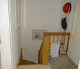 stairs with wooden handrail and carpet, white walls, picture frame, hats on wall