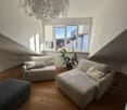 living room with wooden floor, two couches, ottoman, potted plant, chandelier, window with balcony view