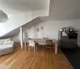 wooden floor, dining table, chairs, couch, white walls, ceiling lamp, white pillar, kitchen cabinet, oven