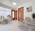 modern office room with white tiles, desk, office chair, wooden table, chairs, plants, lamps, picture frame