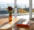 Balcony with a view, dining table with flowers and book, two chairs, round placemats.