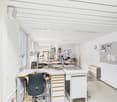 Empty office space with desks, lamps, office chairs, wall mounted bulletin board and clock