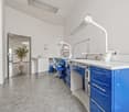 modern office room, white walls, gray floor, blue cabinets, white countertops, medical equipment, sink, potted plant