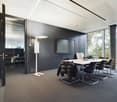 Modern office space with black walls, large windows, a TV mounted on the wall, a conference table with black chairs, and a kitchenette area visible through the open doorway.
