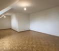 Empty room with white walls, hardwood parquet flooring, and recessed lighting fixtures on the ceiling.