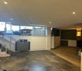 Open room with staircase, modern design, black and gray tiled floor, white walls, visible office equipment, open view to outside