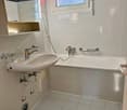Tiled floor, white tiles, vanity with faucet, separate bathtub, shower head, mirror, small window