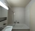 The image shows a bathroom with a white bathtub, a shower head, and white walls.