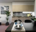 Modern kitchen with light wood cabinets, black countertops, stainless steel appliances, and a dining table with place settings