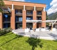 3-story brick apartment building with balconies, outdoor seating area, and landscaped grounds