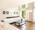 white couches, glass coffee table, sliding glass doors, wooden floor, framed pictures