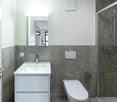 modern bathroom, white tiles, gray wall, sink, mirror, shower, toilet